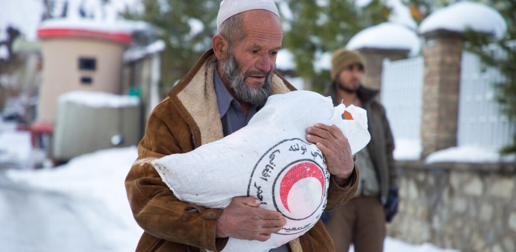 man met hulpgoederen in winter in Afghanistan Rode Kruis