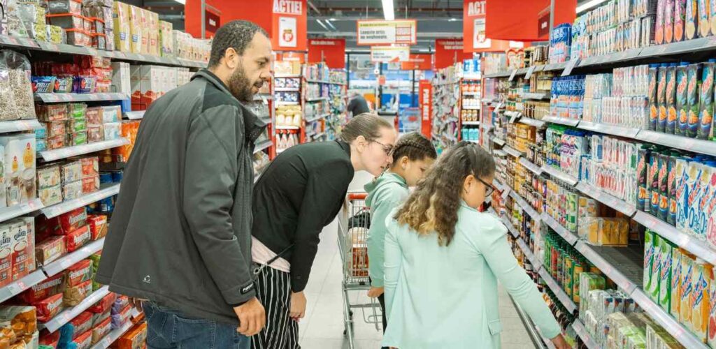 Ouders met kinderen die boodschappen doen met de boodschappenkaart van het Rode Kruis