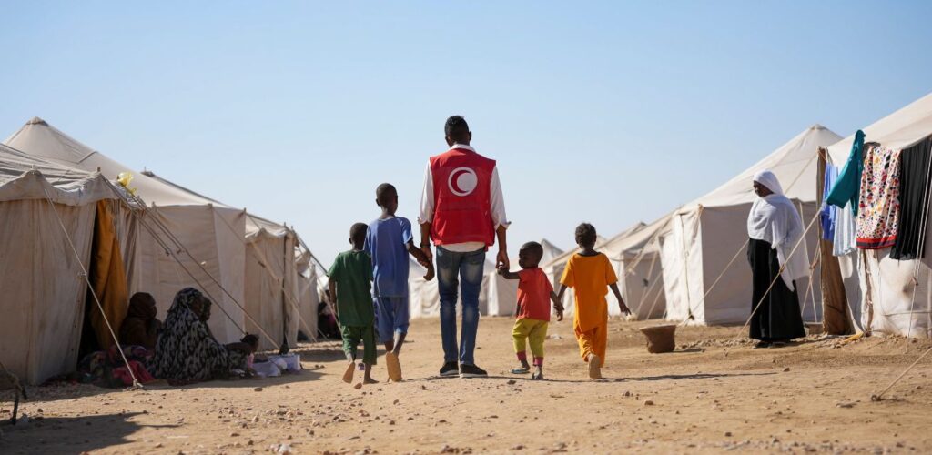 Het Al Nahda-kamp in Atbara, Soedan. Rode Kruis hulpverlener met gevluchte kinderen.