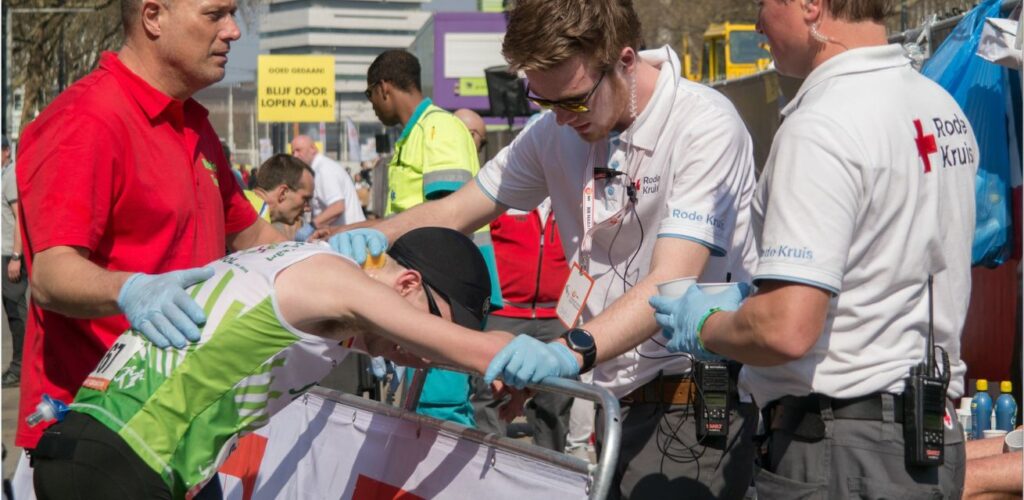 Tijdens de marathon staan vrijwilligers van het Rode Kruis bij de finish om renners op te vangen na een zware tocht.