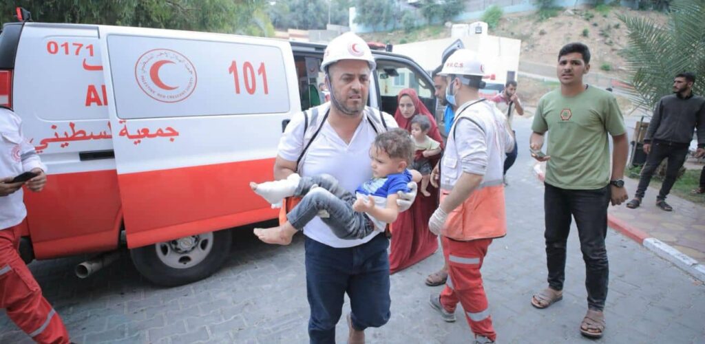 Hulpverleners van het Rode Kruis in Gaza tilt een gewond jongetje naar het ziekenhuis