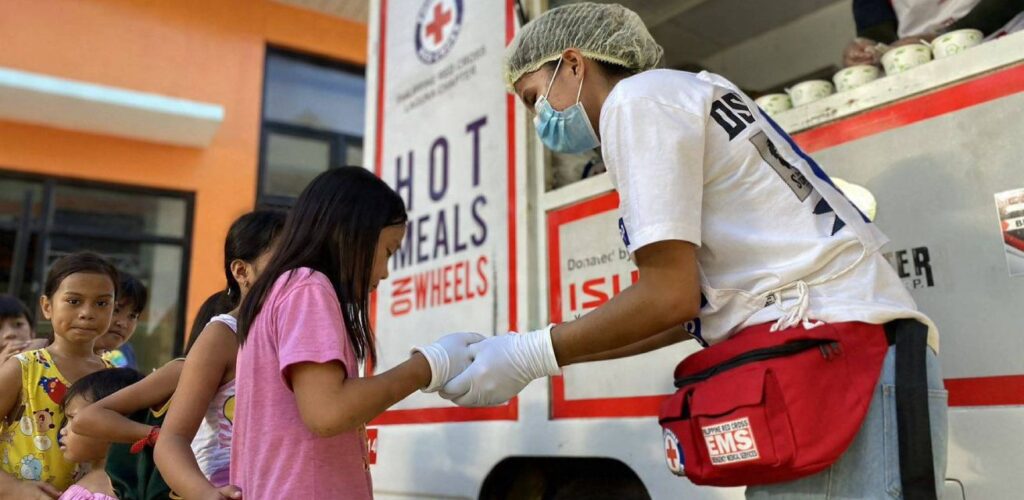 Hulpverleners Rode Kruis in de Filipijnen delen warme maaltijden uit aan mensen die hun huis moesten verlaten