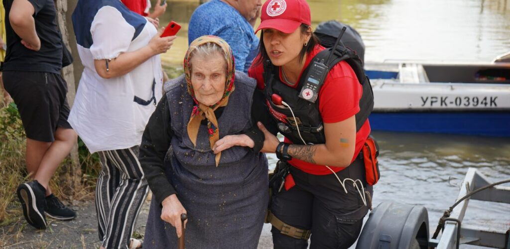 In Oekraïne helpt een vrijwilliger een oudere vrouw naar een veilige plek.