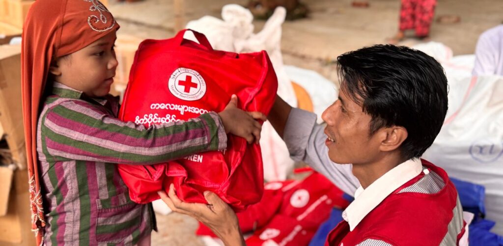 In Myanmar helpt een Rode Kruis-vrijwilliger een kind na de aardbevingen.