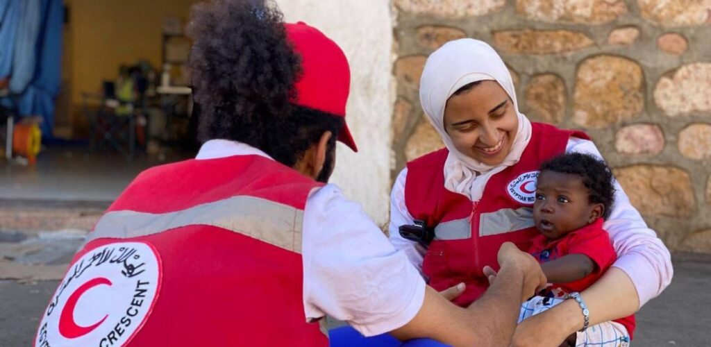 Mensen die vluchten uit Soedan worden geholpen door Rode Kruis-vrijwilligers aan de grens.