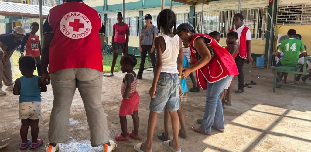 Hulpverleners Rode Kruis doen activiteit met kinderen op basisschool in Jamaica na orkaan Melissa