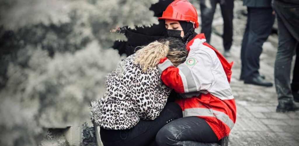 Hulpverlener van de Iraanse Rode Halve Maan biedt ondersteuning aan een vrouw.