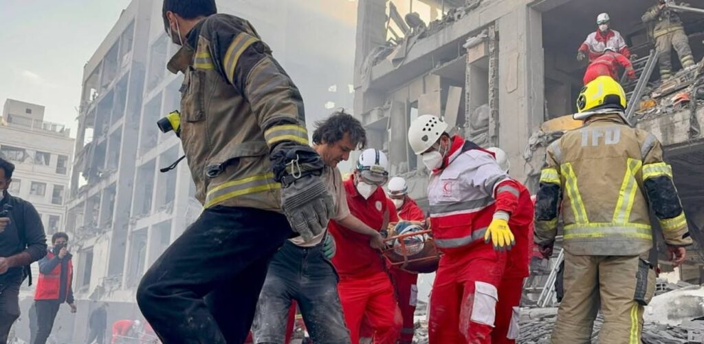 Hulpverleners van de Rode Halve Maan voeren een reddingsoperatie uit in Teheran na een luchtaanval.