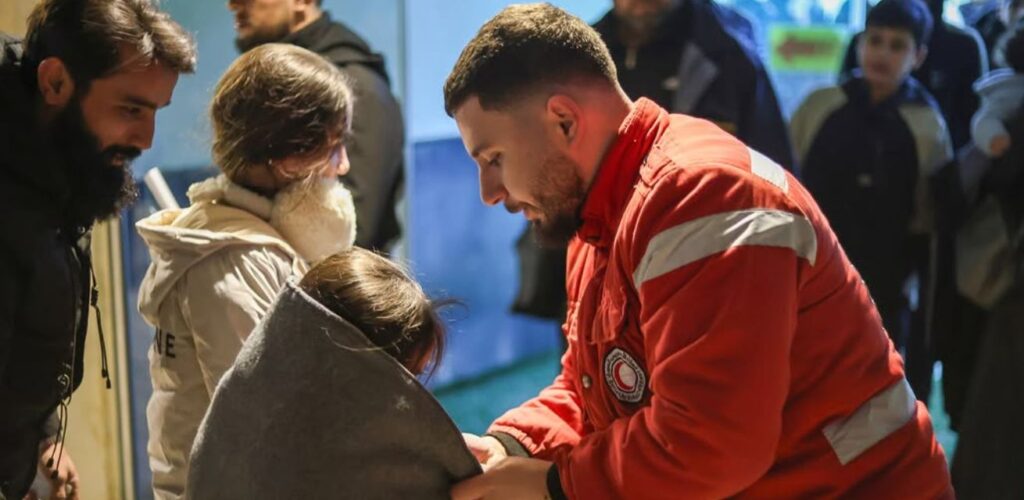 Hulpverleners van de Syrische Rode Halve Maan delen dekens uit aan gevluchte gezinnen uit Libanon.