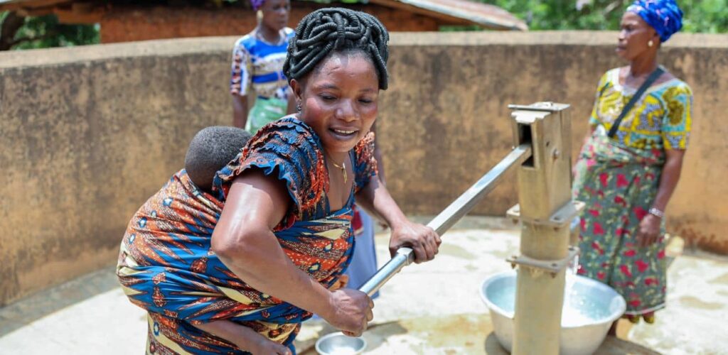 Vrouw in Togo bij waterput door Rode Kruis en community beheerd