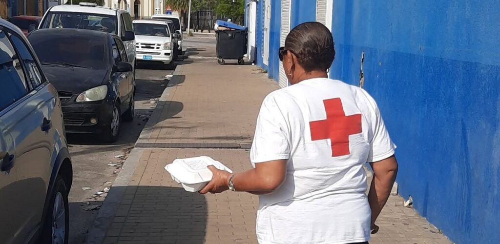 Een hulpverlener van het Rode Kruis Aruba deelt voedselpakketten uit aan mensen in voedselnood.