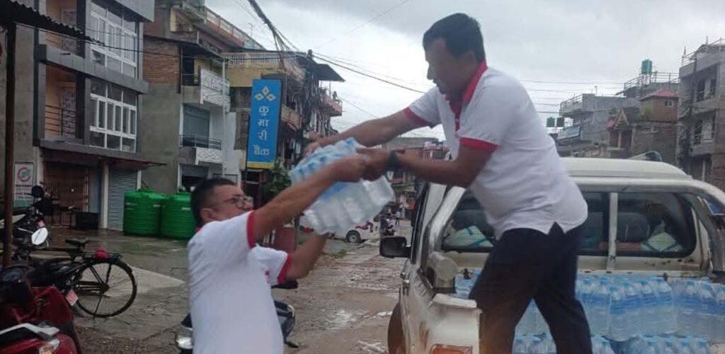 Vrijwilligers van het Nepalese Rode Kruis delen water uit aan de getroffenen van de overstroming