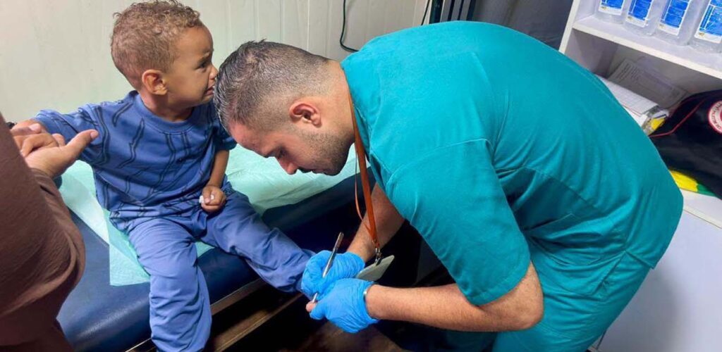 Een hulpverlener helpt een kind die scherven in zijn voet heeft