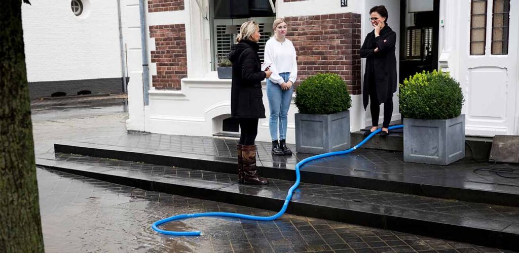 Een winkelier pompt water uit een ondergelopen garage.
