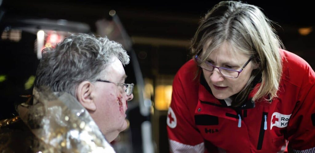 rode kruis ehbo vrijwilliger helpt gewonde man