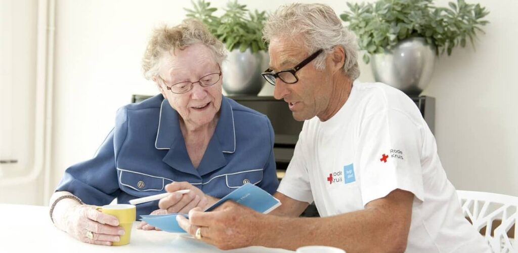 rode kruis vrijwilliger helpt oudere mevrouw